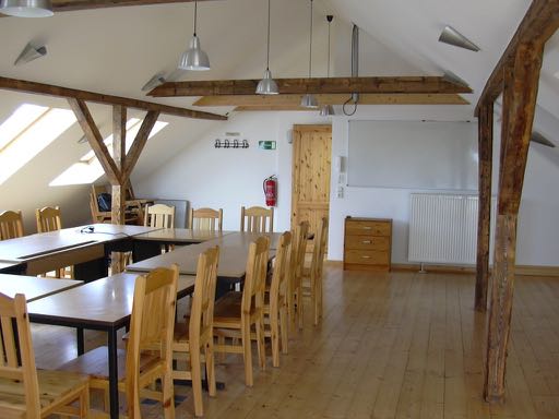 Das Bild zeigt den Schulungsraum unter dem Dach mit acht Tischen, zwölf Stühlen und Whiteboard